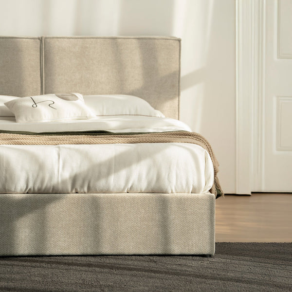 Cama Madrid Queen tapizada en beige, con sábanas blancas y luz de tarde