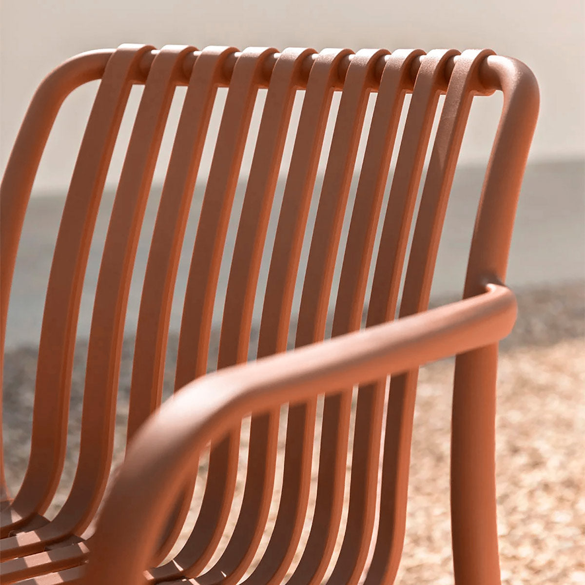 Detalle reposa brazos de silla de exterior Menorca, fondo de patio de piedras