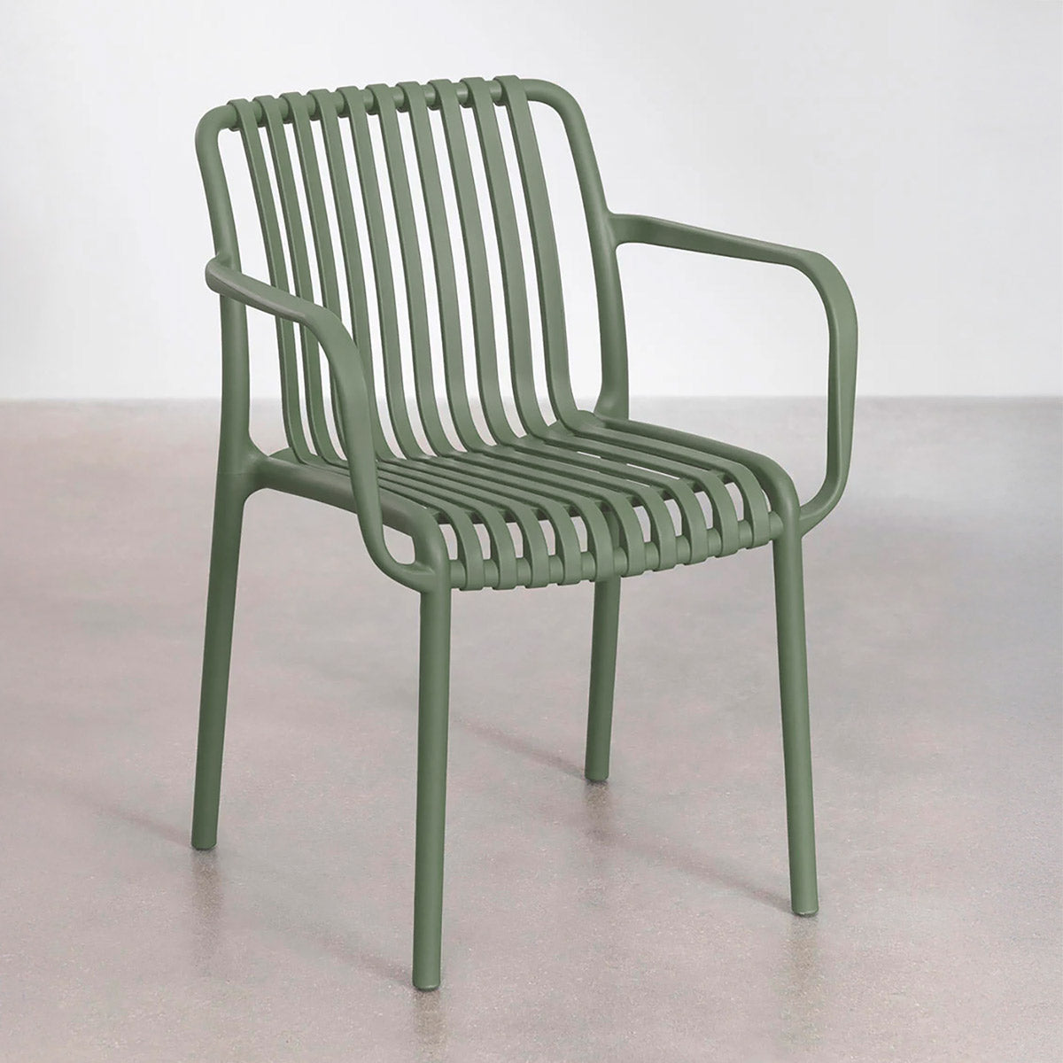 Silla de Exterior Menorca verde frente a pared blanca sobre piso de concreto