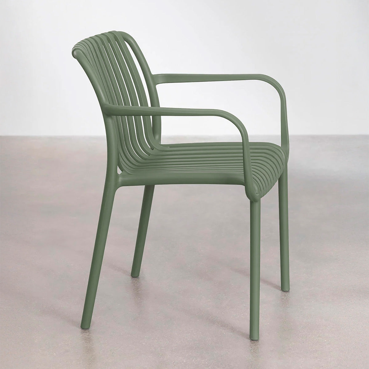 Silla de exterior Menorca verde vista lateral frente a pared blanca sobre piso de concreto